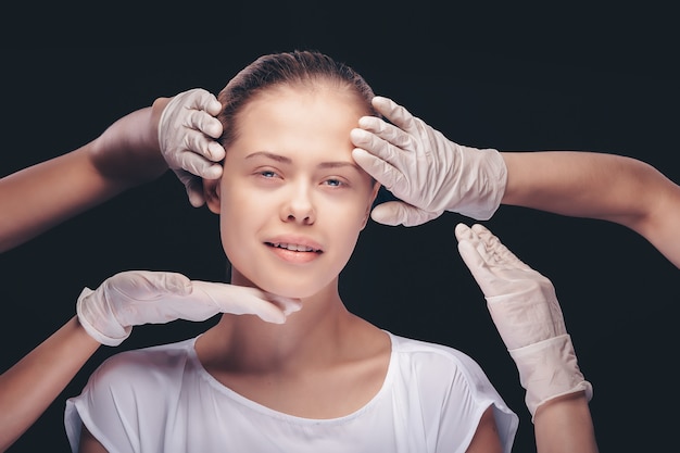 Mulher jovem com os olhos fechados fazendo um exame médico da pele do rosto por médicos de plástico
