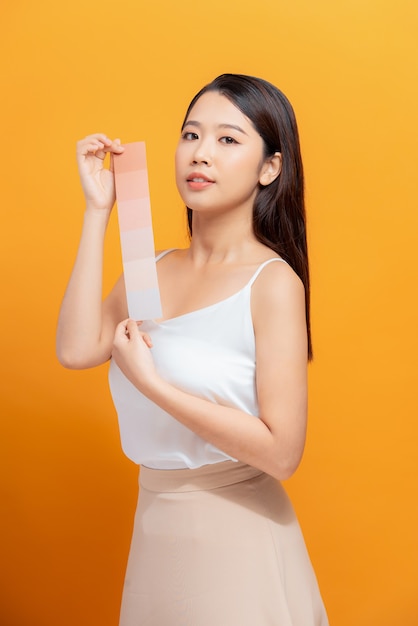 Mulher jovem com paleta de tinta na cor de fundo