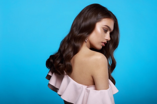 Mulher jovem com penteado ondulado vestida com blusa rosa