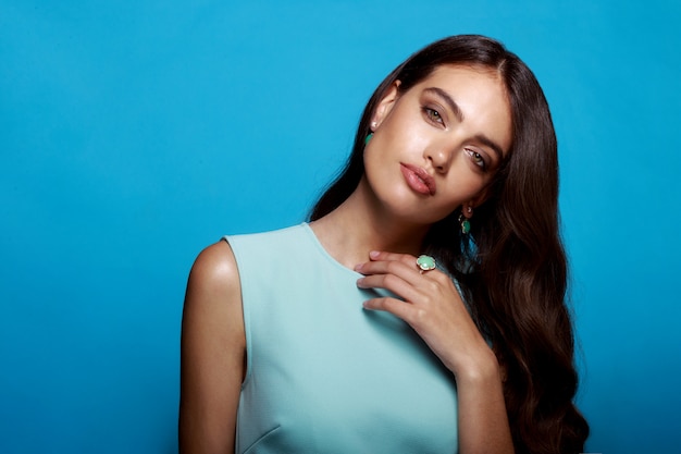 Mulher jovem com penteado ondulado vestida de vestido azul