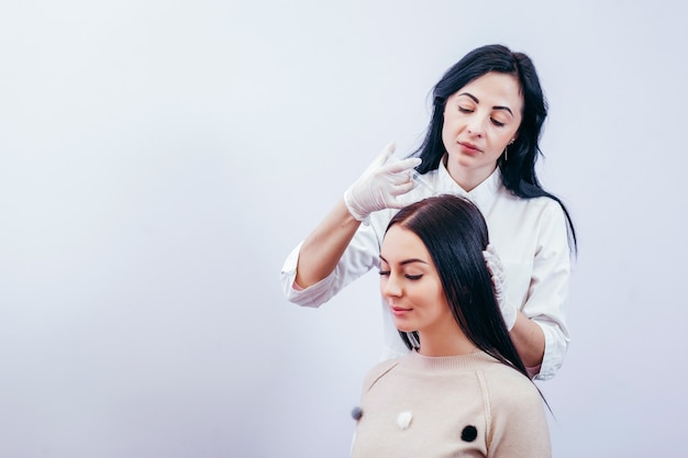 Mulher jovem com problema de queda de cabelo recebendo injeção, close-up