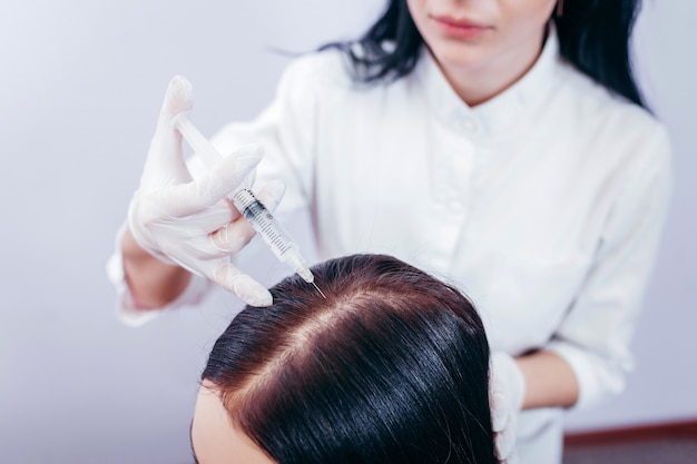 Mulher jovem com problema de queda de cabelo recebendo injeção, close-up