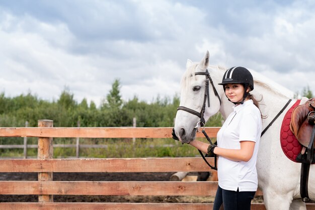 Há uma mulher andando a cavalo pulando sobre uma cerca de madeira