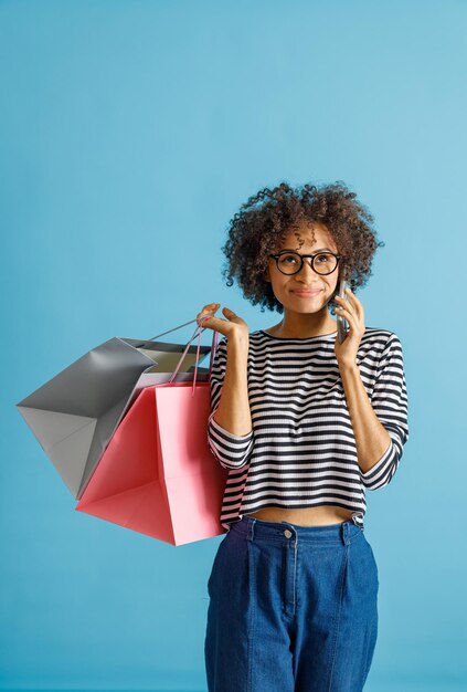 Mulher jovem com sacolas de compras falando no celular