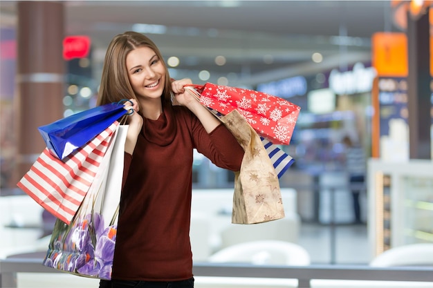 Mulher jovem com sacolas de compras no fundo