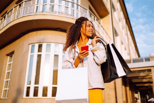 Mulher jovem com sacos de compras caminhando na rua Venda de compras e conceito de pessoas felizes