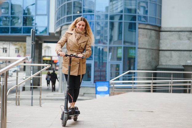 Mulher jovem com scooter elétrico na cidade