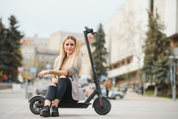 Mulher jovem com scooter elétrico na cidade