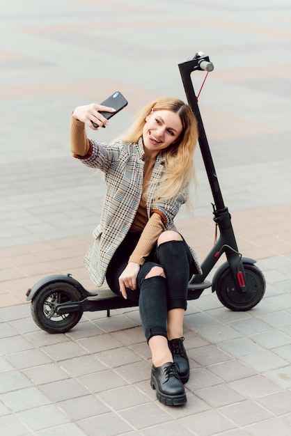 Foto mulher jovem com scooter elétrico na cidade