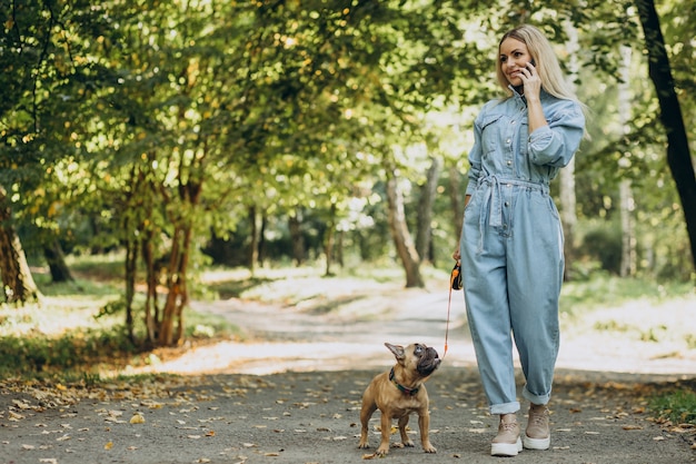 Mulher jovem com seu buldogue francês de estimação no parque