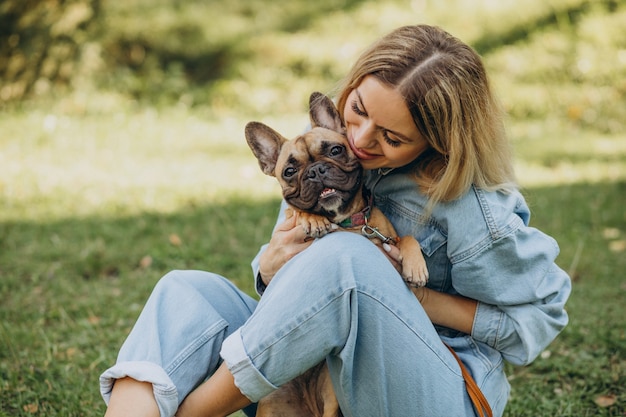 Mulher jovem com seu buldogue francês de estimação no parque