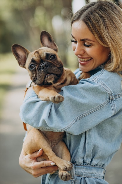 Mulher jovem com seu buldogue francês de estimação no parque