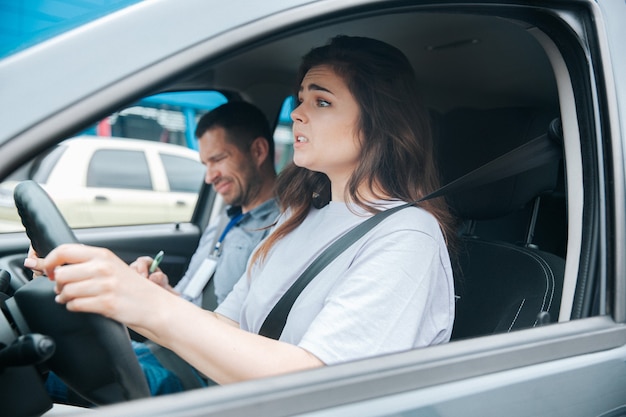 Mulher jovem com seu instrutor de automóvel em um carro