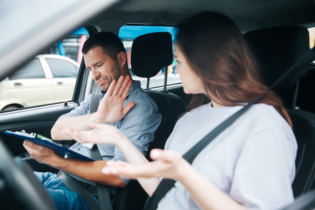 Mulher jovem com seu instrutor de automóvel em um carro