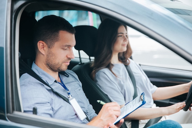 Mulher jovem com seu instrutor de automóvel em um carro