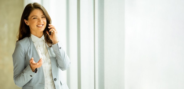 Mulher jovem, com, telefone móvel, por, a, janela