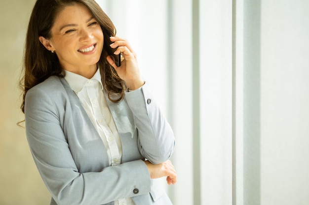 Mulher jovem, com, telefone móvel, por, a, janela