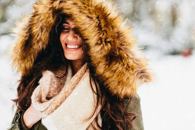 Mulher jovem com um capuz de pele no parque na neve