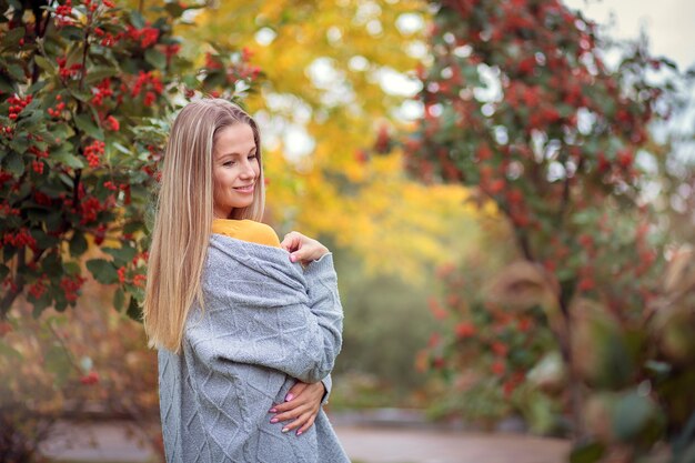 Mulher jovem com um casaco de lã cinza no parque de outono