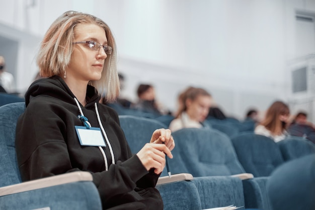 Mulher jovem com um distintivo em branco sentada na sala de conferências