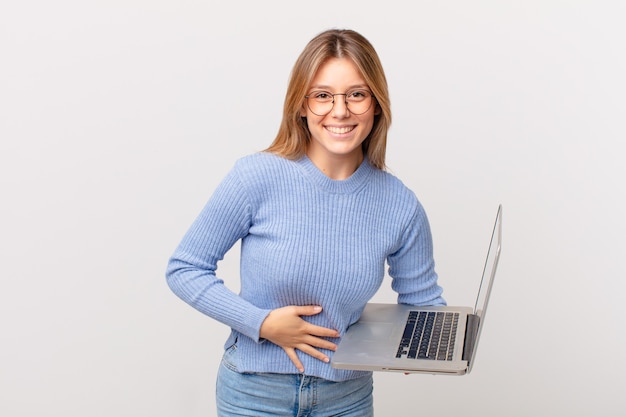 Mulher jovem com um laptop rindo alto de uma piada hilária