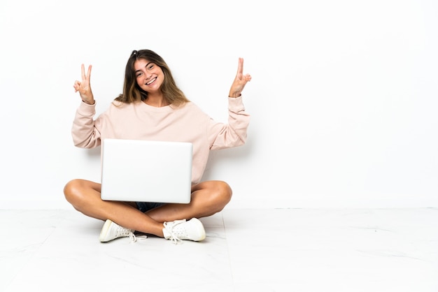 Mulher jovem com um laptop sentada no chão isolada