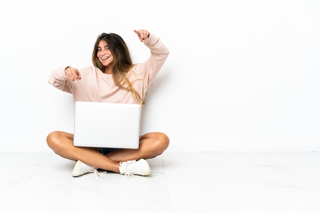 Mulher jovem com um laptop sentada no chão isolada