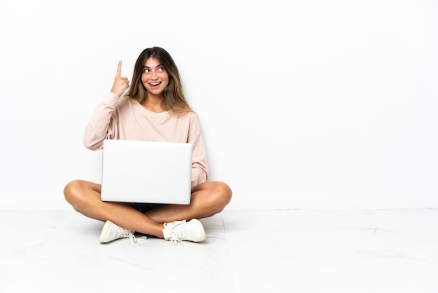 Mulher jovem com um laptop sentada no chão isolada