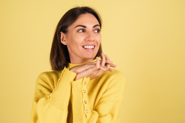 Mulher jovem com um suéter amarelo quente com um sorriso sonhador no rosto