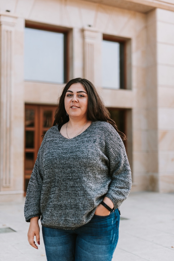 Mulher jovem com um suéter ao lado de um prédio
