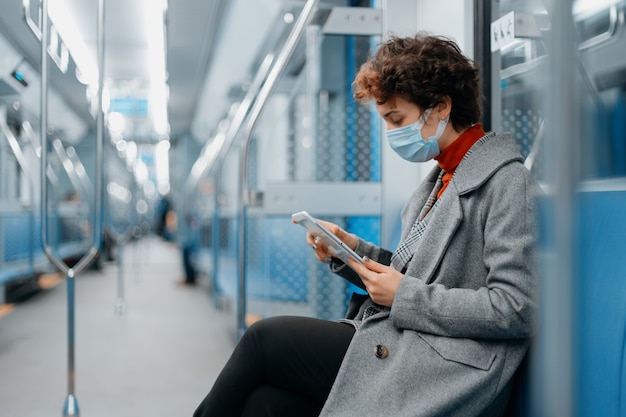 Mulher jovem com um tablet digital sentada em um vagão vazio do metrô