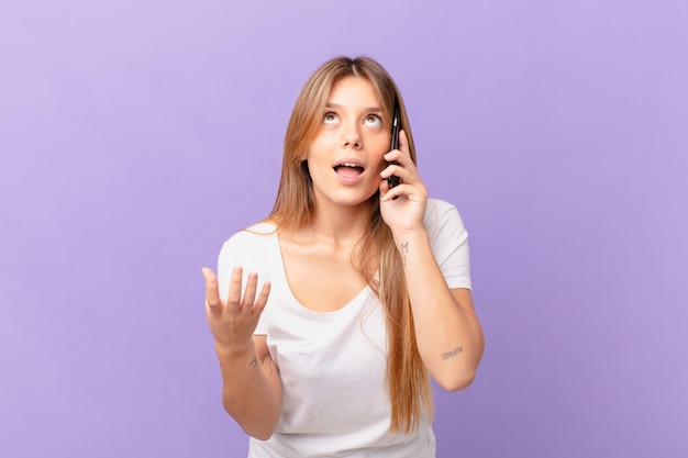 Foto mulher jovem com um telefone celular parecendo desesperada, frustrada e estressada