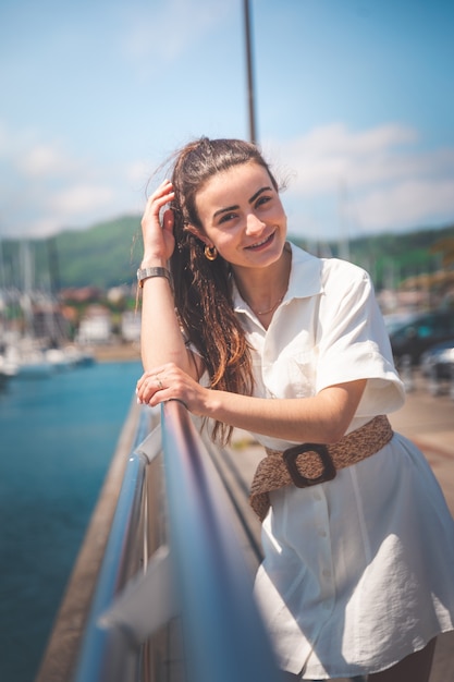 Mulher jovem com um vestido branco em um porto