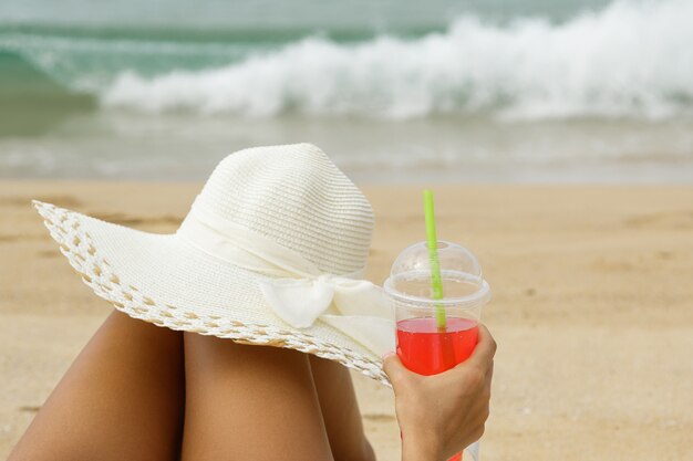 Mulher jovem com uma bebida refrescante vermelha na praia