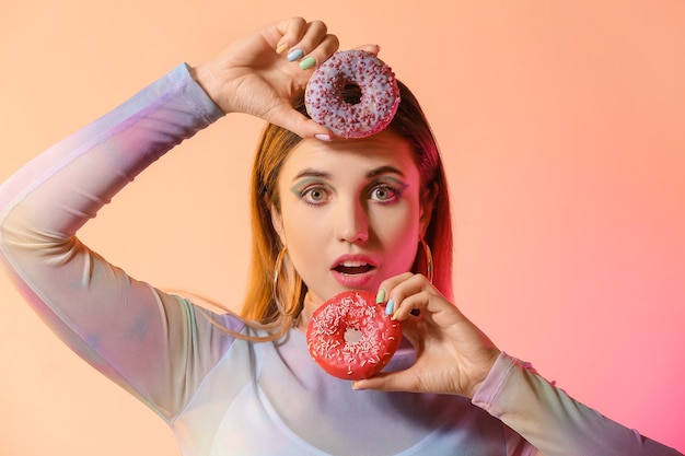 Mulher jovem com uma bela manicure e donuts em rosa