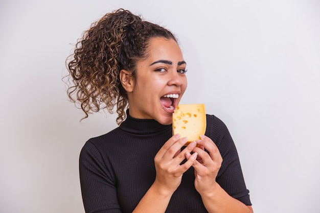 Foto mulher jovem com uma fatia de queijo na mão. mulher comendo queijo parmesão