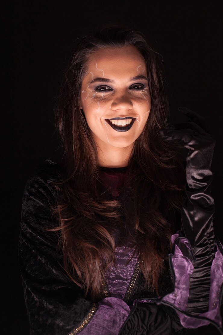 Foto mulher jovem com uma roupa de bruxa para o dia das bruxas sobre fundo preto