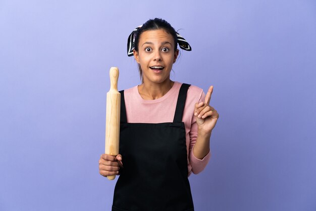 Mulher jovem com uniforme de chef com a intenção de descobrir a solução enquanto levanta um dedo
