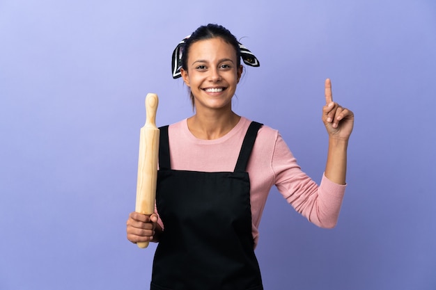 Foto mulher jovem com uniforme de chef mostrando e levantando um dedo em sinal dos melhores