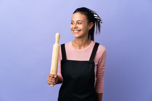 Mulher jovem com uniforme de chef, olhando para o lado e sorrindo