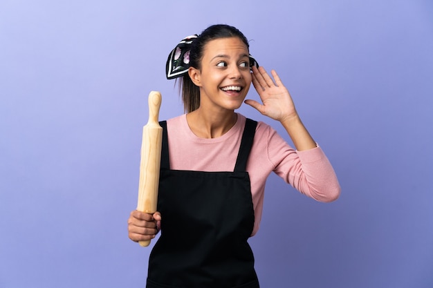 Mulher jovem com uniforme de chef ouvindo algo colocando a mão na orelha