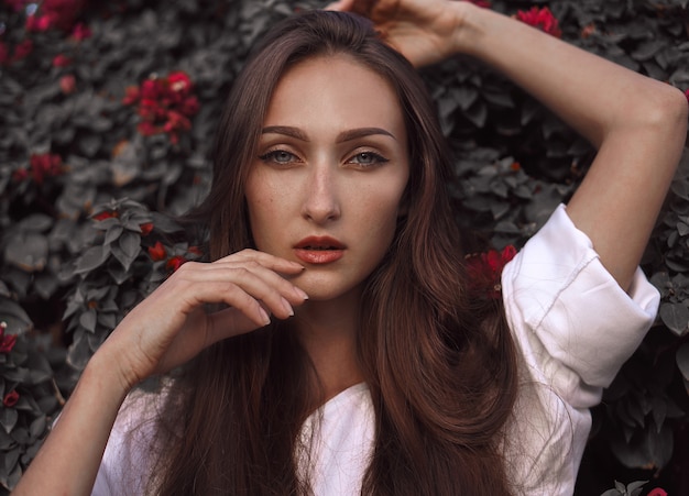 Mulher jovem com vestido branco e cabelo bonito rodeado de flores