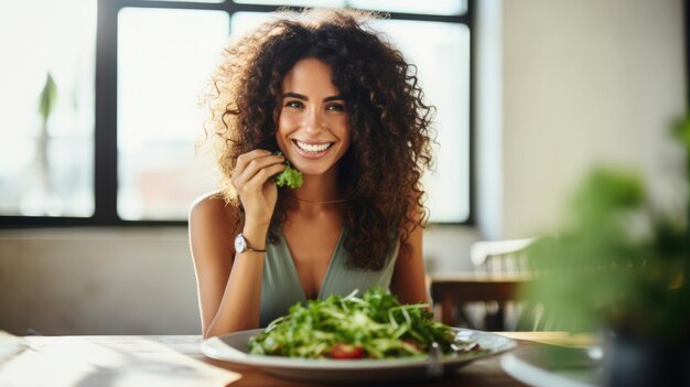 Foto mulher jovem come uma salada saudável com legumes frescos enquanto está sentada em uma mesa em casa em um café