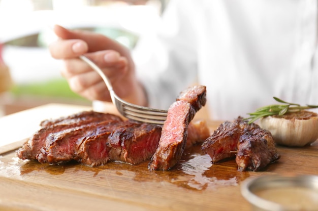 Mulher jovem comendo bife grelhado em restaurante