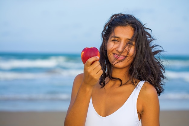 Mulher jovem comendo fruta na praia