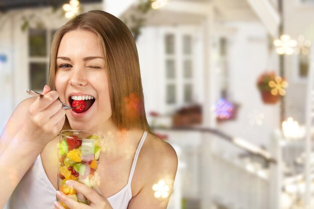 Foto mulher jovem comendo frutas de vidro no fundo desfocado