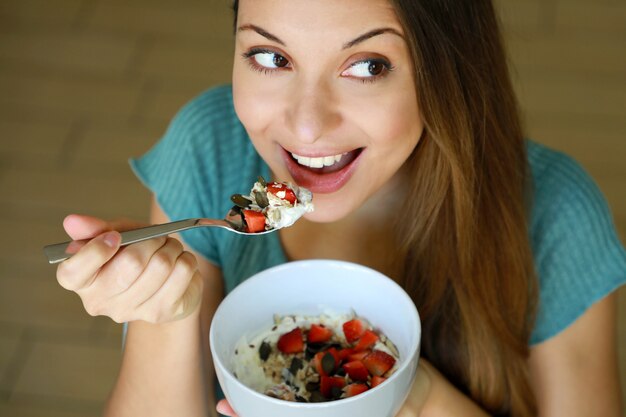 Mulher jovem comendo muesli de cereais e frutas