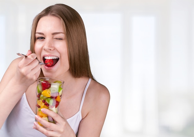 Mulher jovem comendo salada de frutas