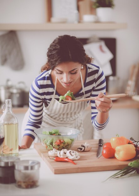 Foto mulher jovem comendo salada fresca em cozinha moderna