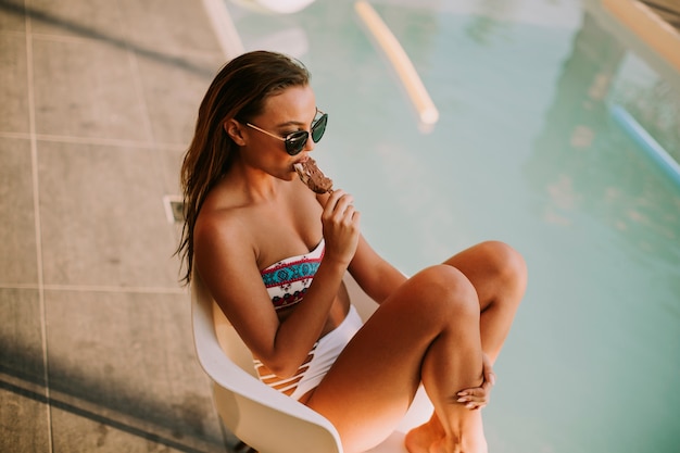 Foto mulher jovem, comendo sorvete, perto, a, piscina, em, hott, dia verão